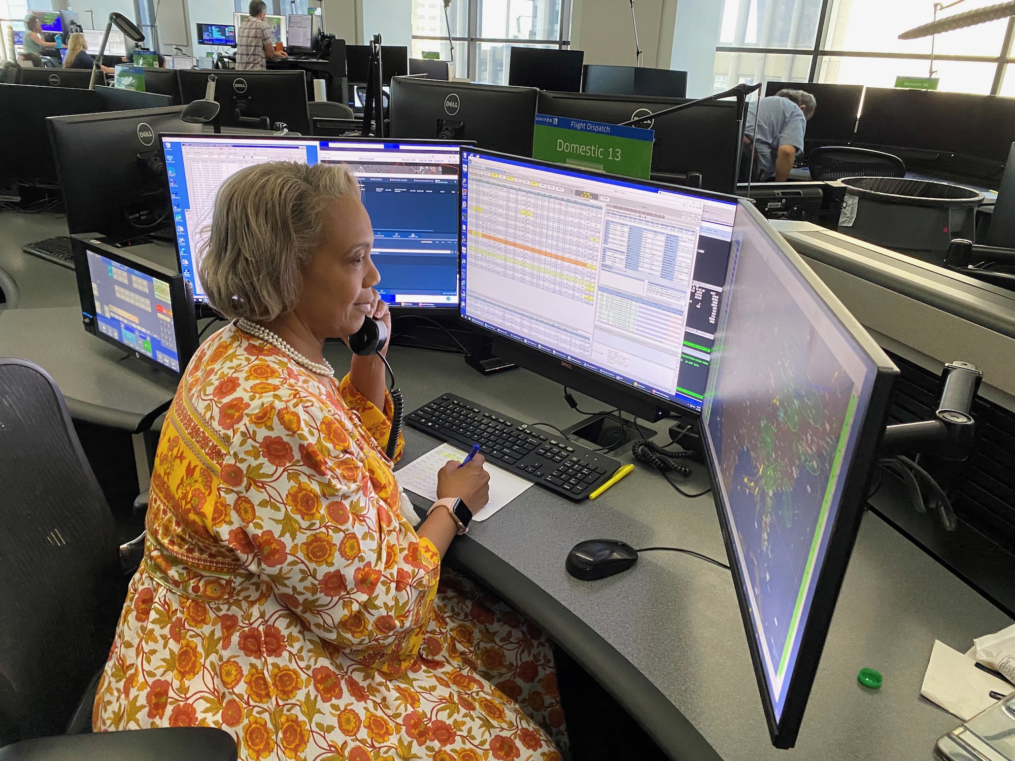 a woman sitting at a desk with multiple computer screens