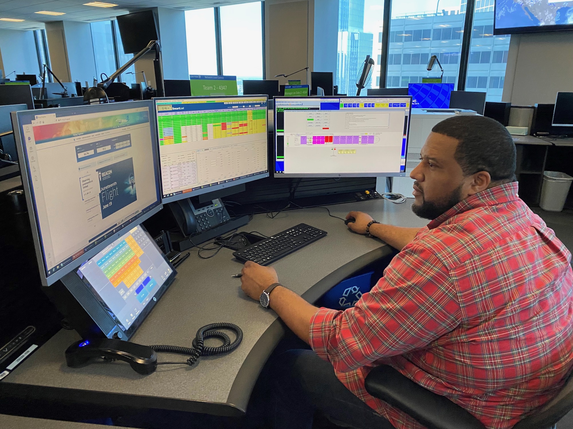 a man sitting at a desk with multiple computer screens