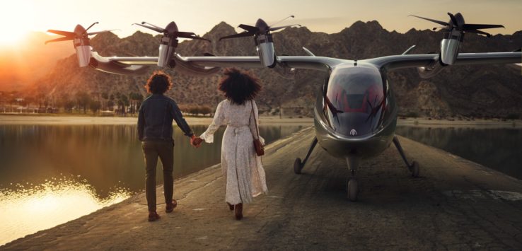 a man and woman holding hands walking on a concrete walkway with a plane and water