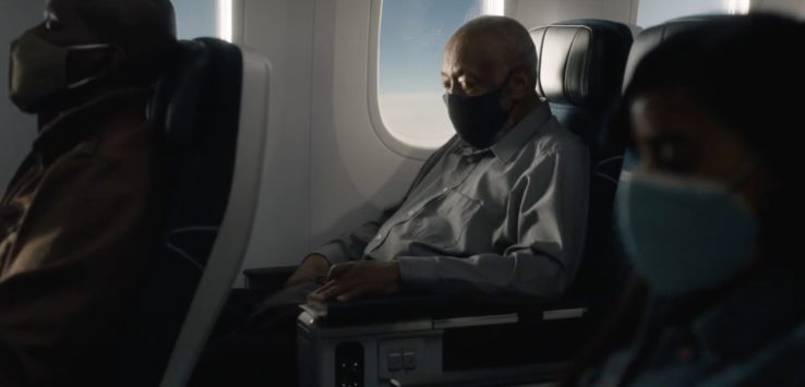 a man wearing a face mask sitting in a plane