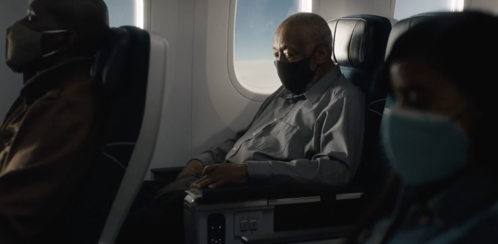 a man wearing a face mask sitting in a plane