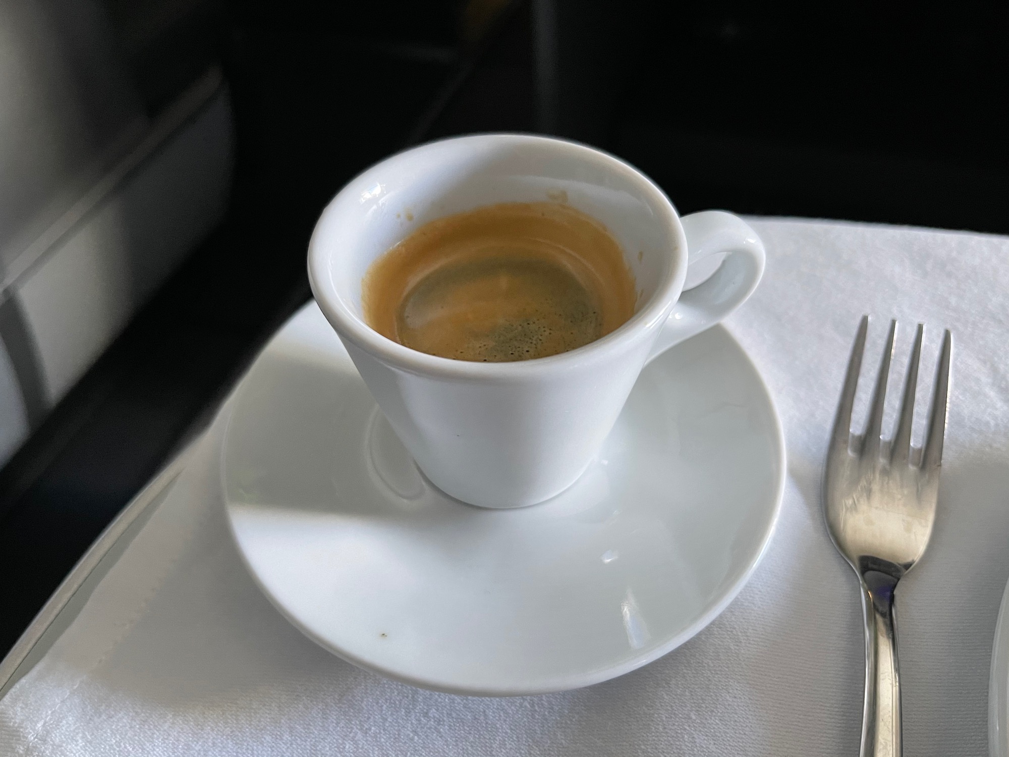 a cup of coffee on a saucer and a fork