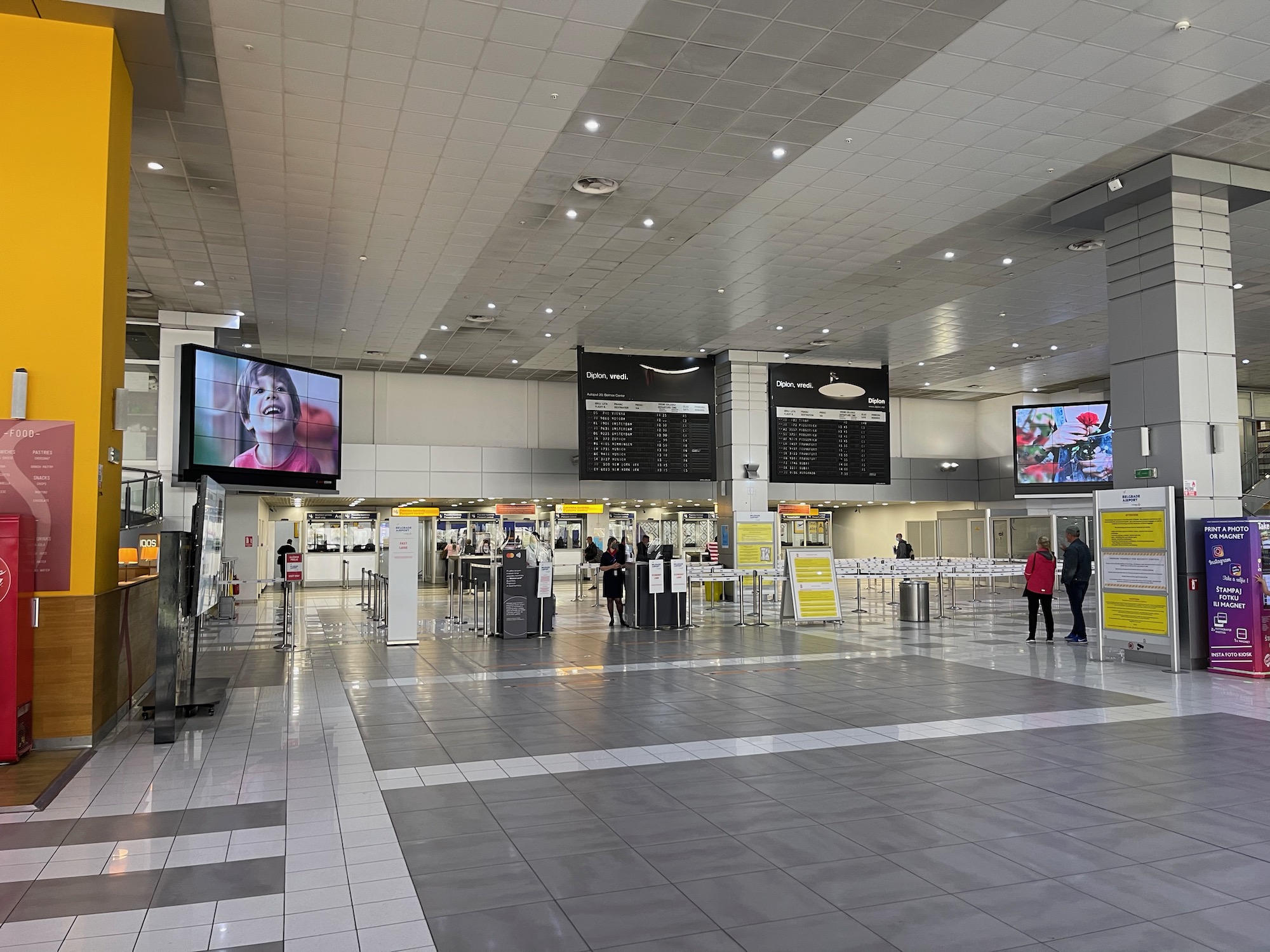 a large airport terminal with a television and people walking