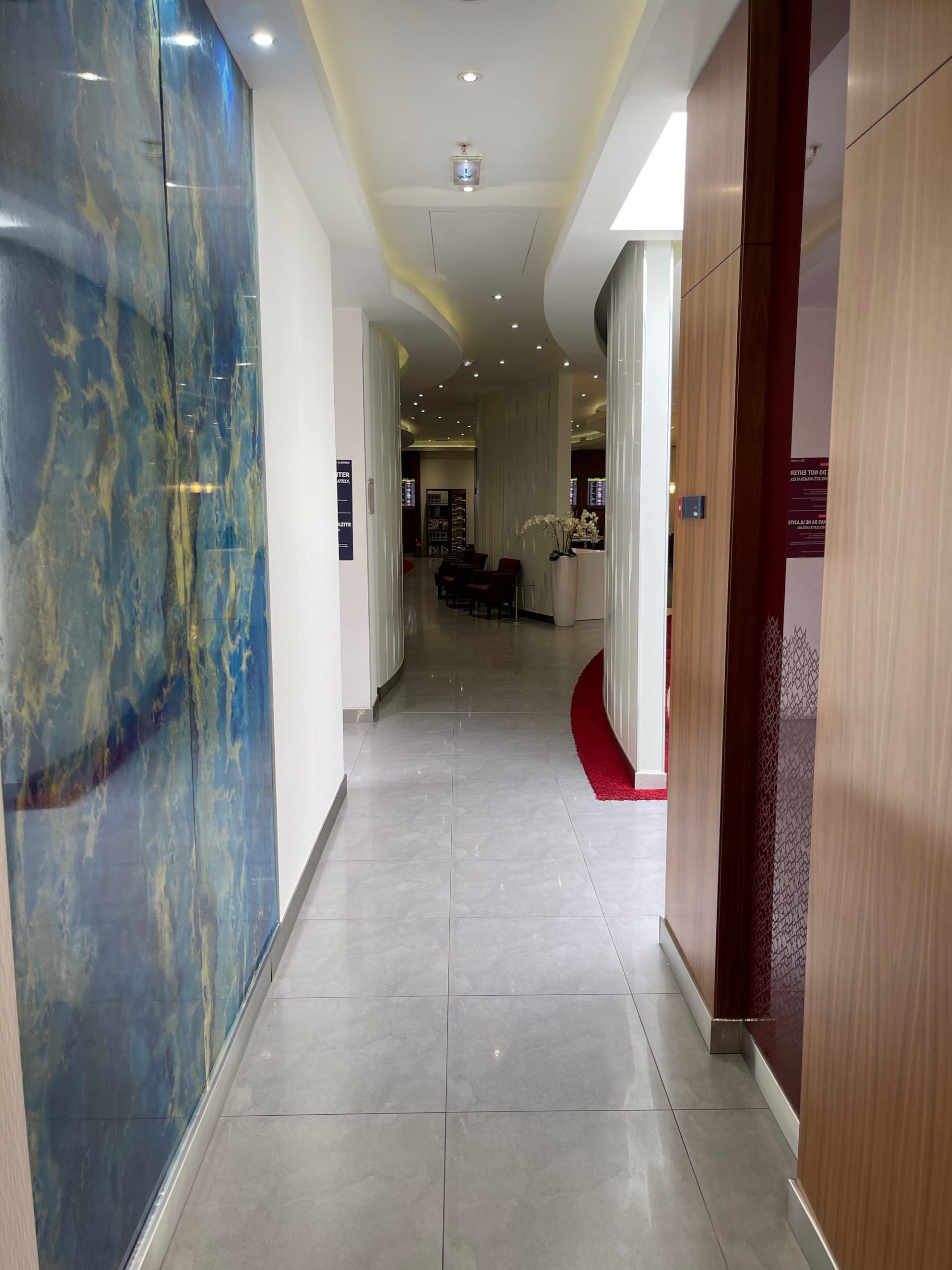 a hallway with a marble wall and a red carpet