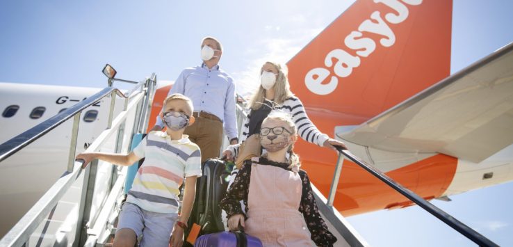 a group of people wearing face masks and standing on an airplane