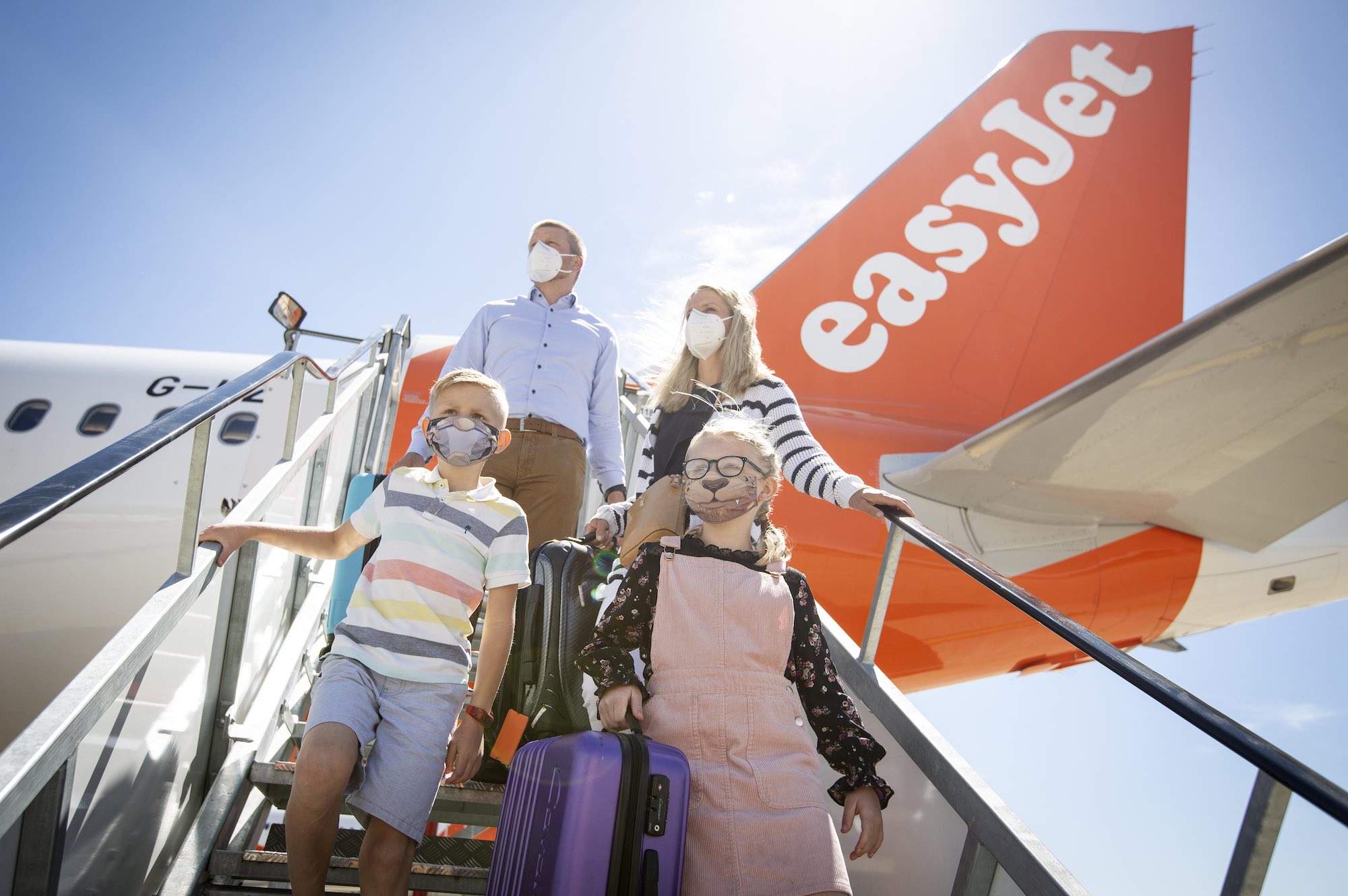 a group of people wearing face masks and standing on an airplane