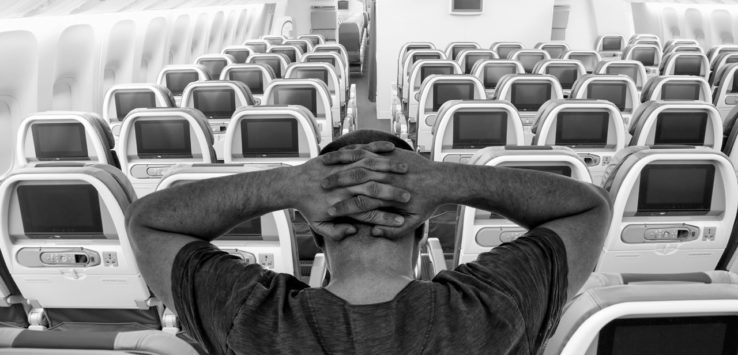 a man sitting in an airplane with his hands on his head