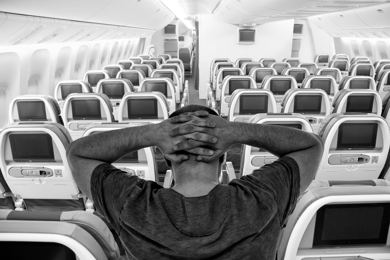 a man sitting in an airplane with his hands on his head