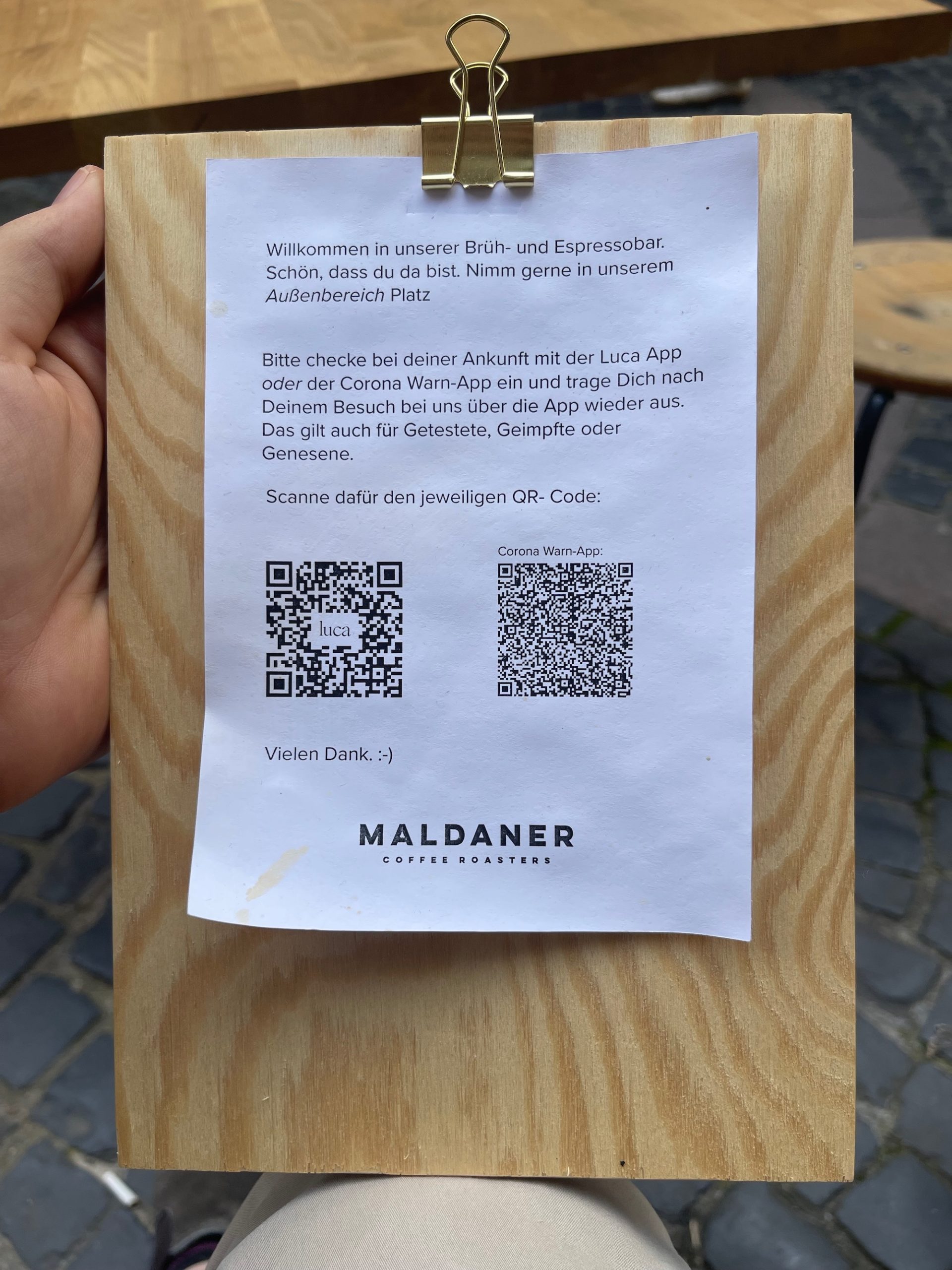 a hand holding a piece of paper with a qr code attached to a wood board
