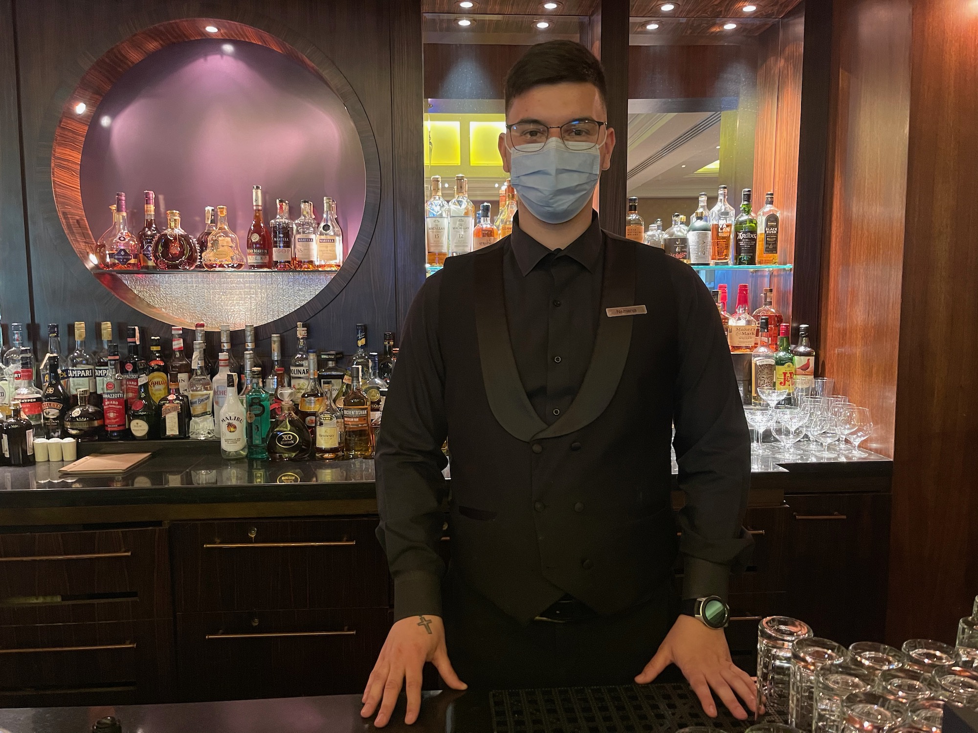 a man wearing a face mask standing in front of a bar