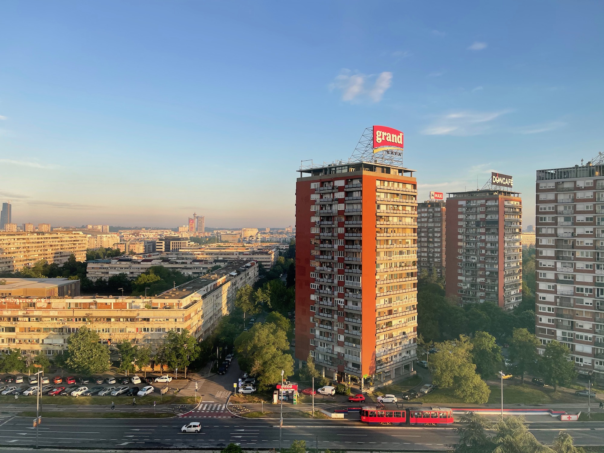 a group of tall buildings with trees and cars in the background