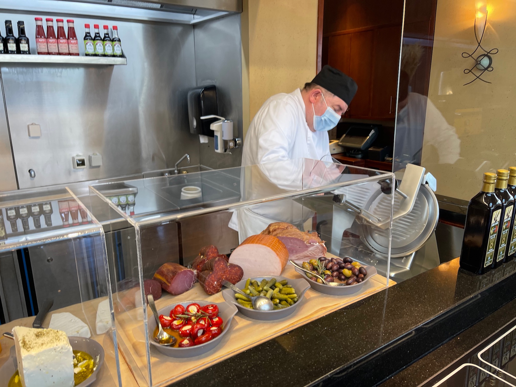 a man in a white coat behind a glass case with food