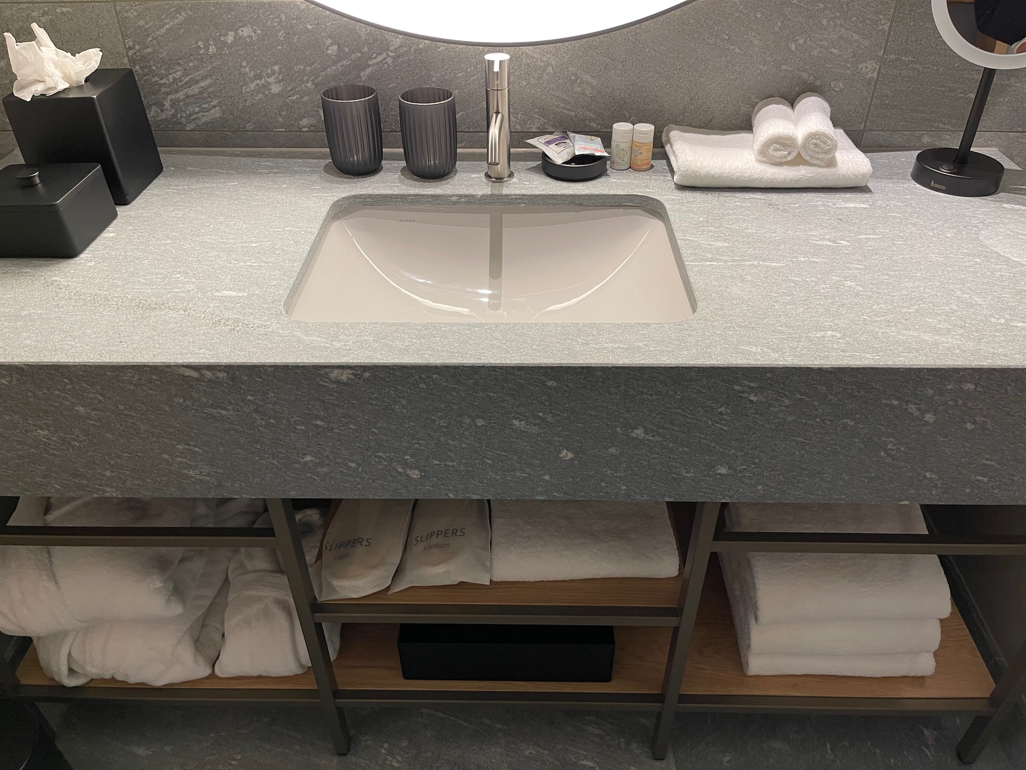 a sink with a round mirror above it