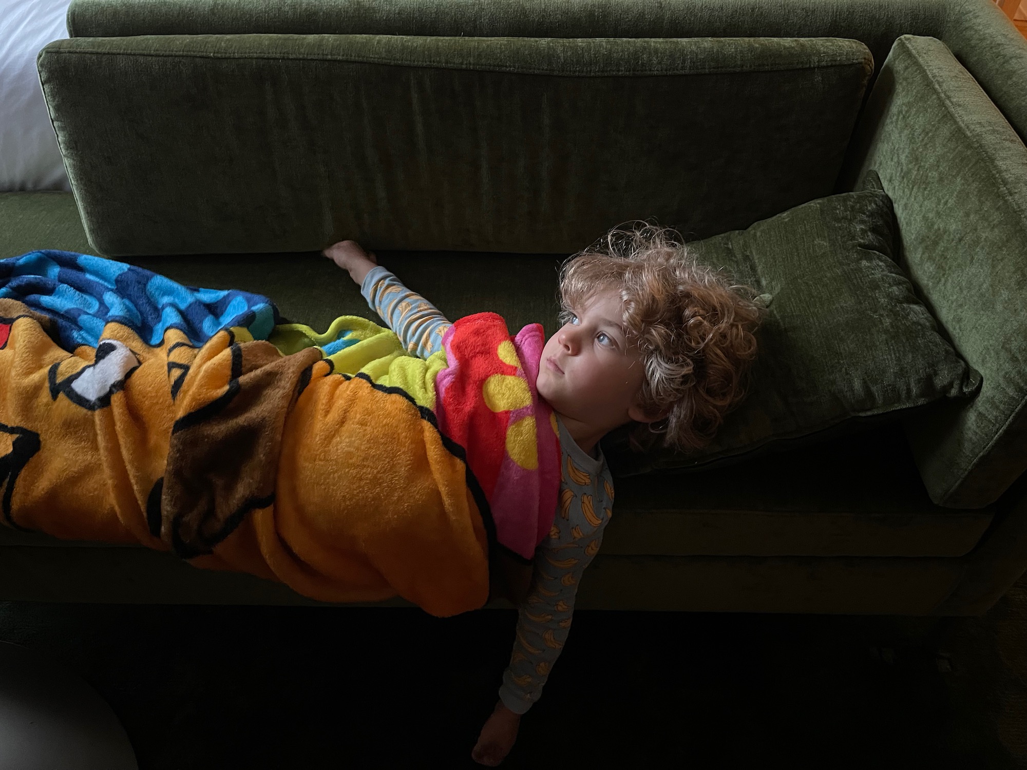 a child wrapped in a blanket lying on a couch