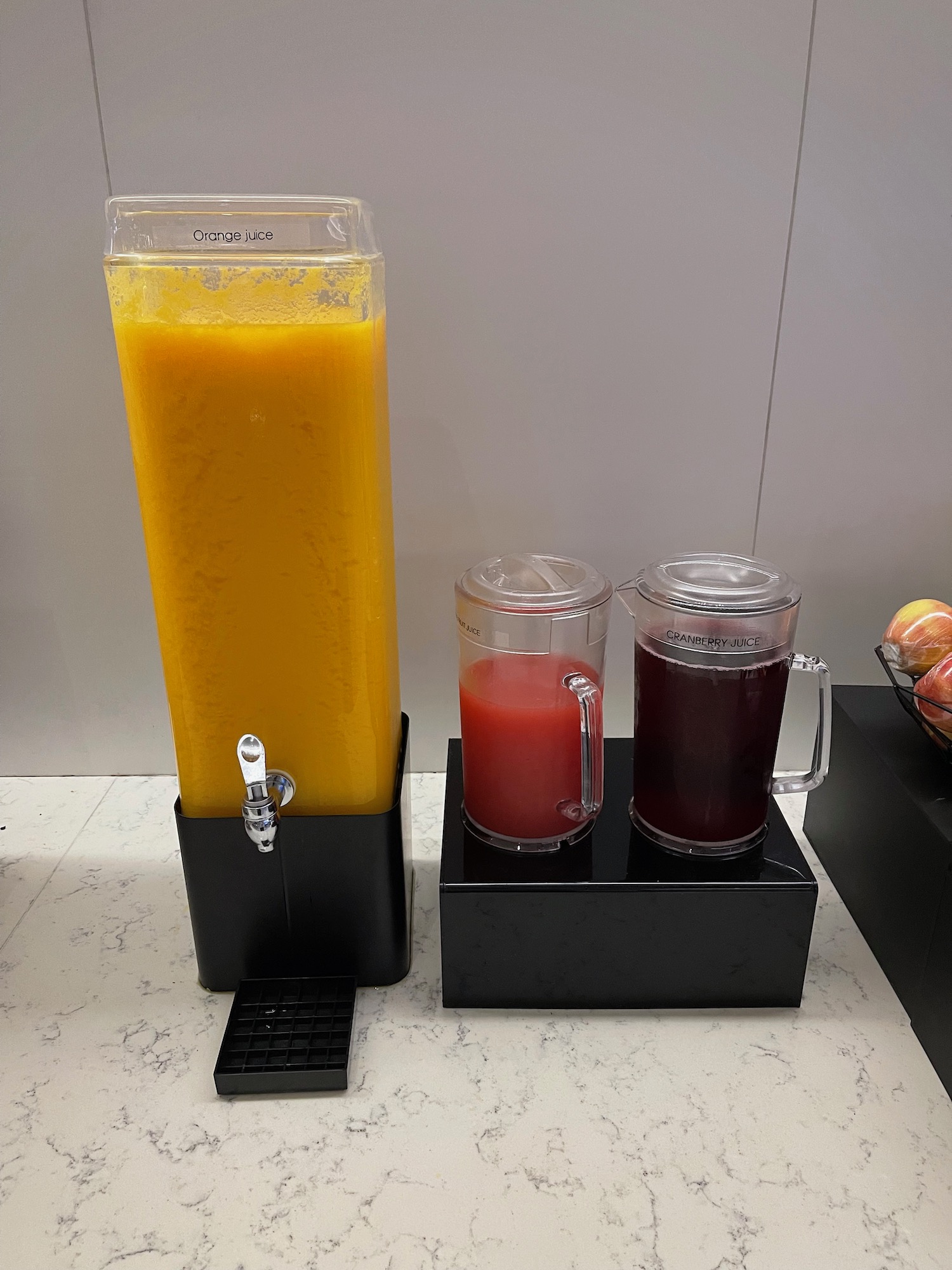 a beverage dispenser and two glasses of juice