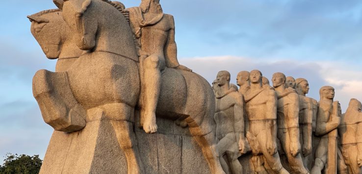 a stone statue of a group of men riding horses