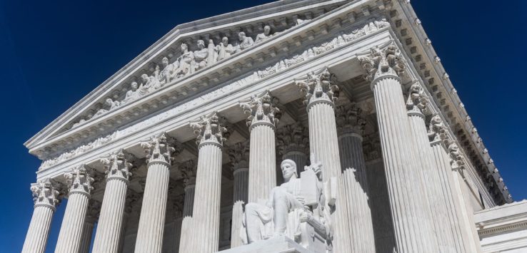 a statue of a man sitting on a pedestal in front of United States Supreme Court Building
