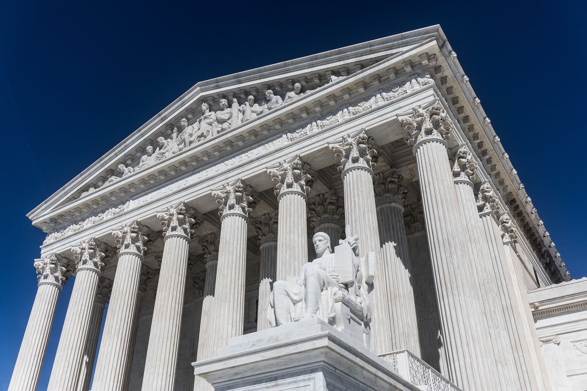 a statue of a man sitting on a pedestal in front of United States Supreme Court Building