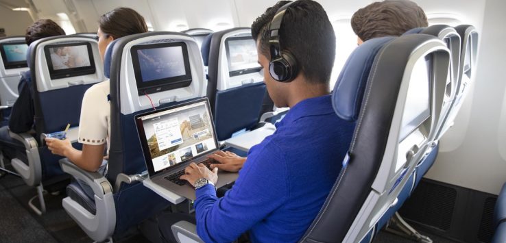 a group of people sitting in an airplane with a laptop
