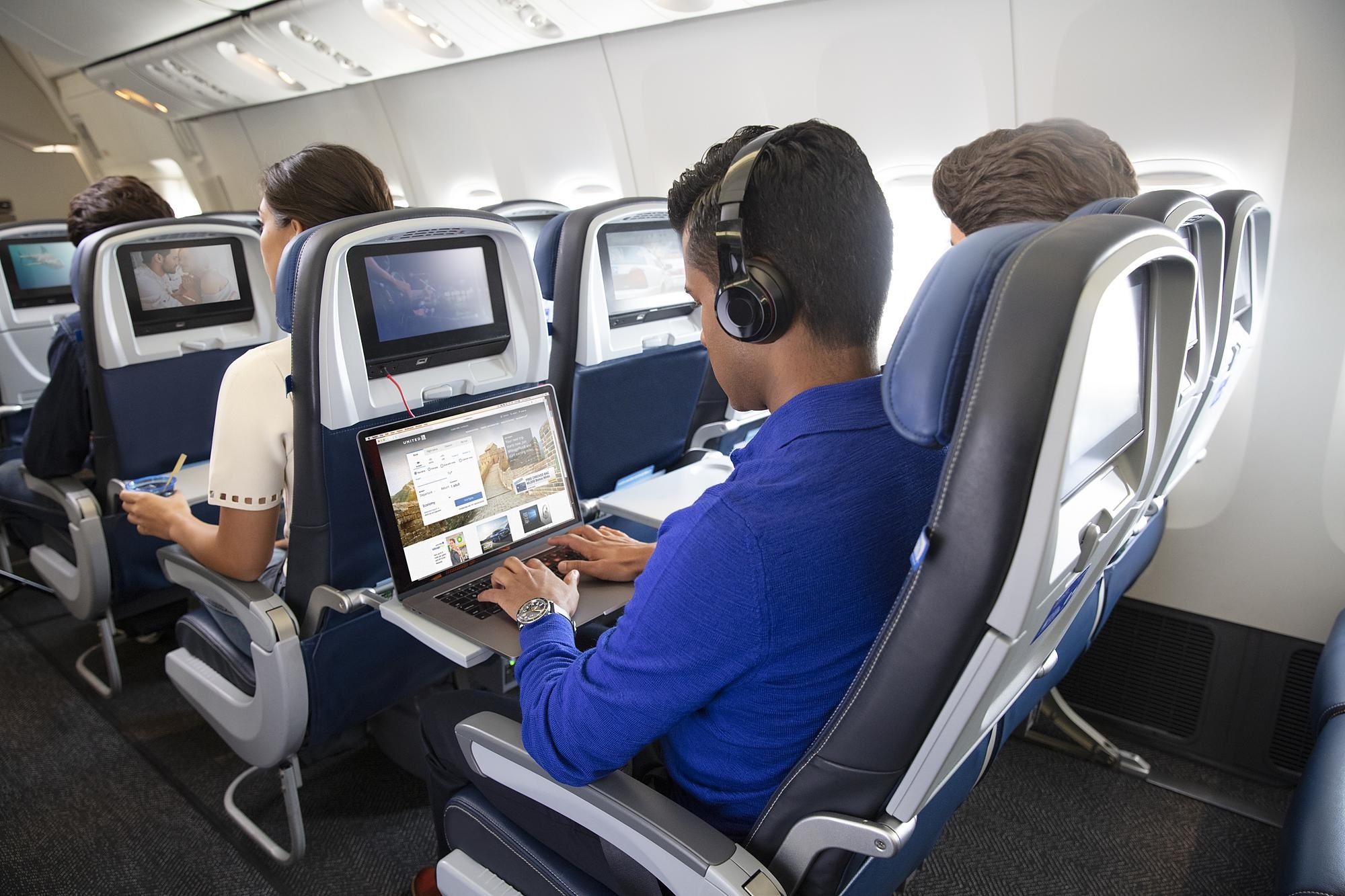 a group of people sitting in an airplane with a laptop