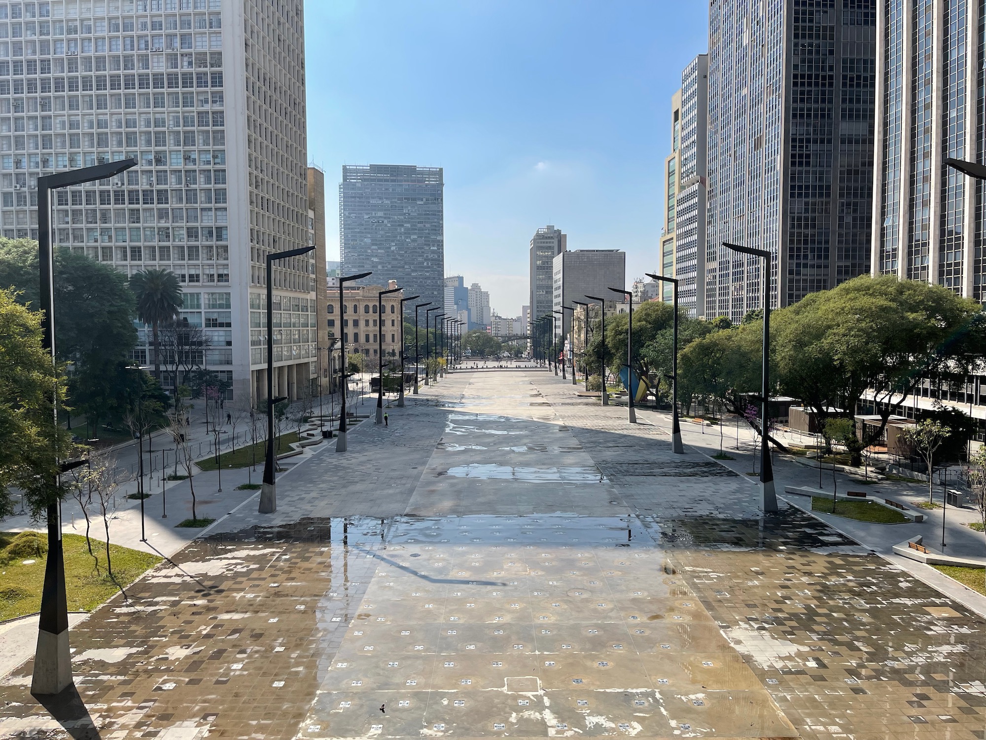 a wet sidewalk with tall buildings in the background