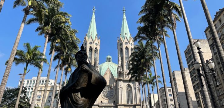 a statue in front of São Paulo Cathedral with palm trees