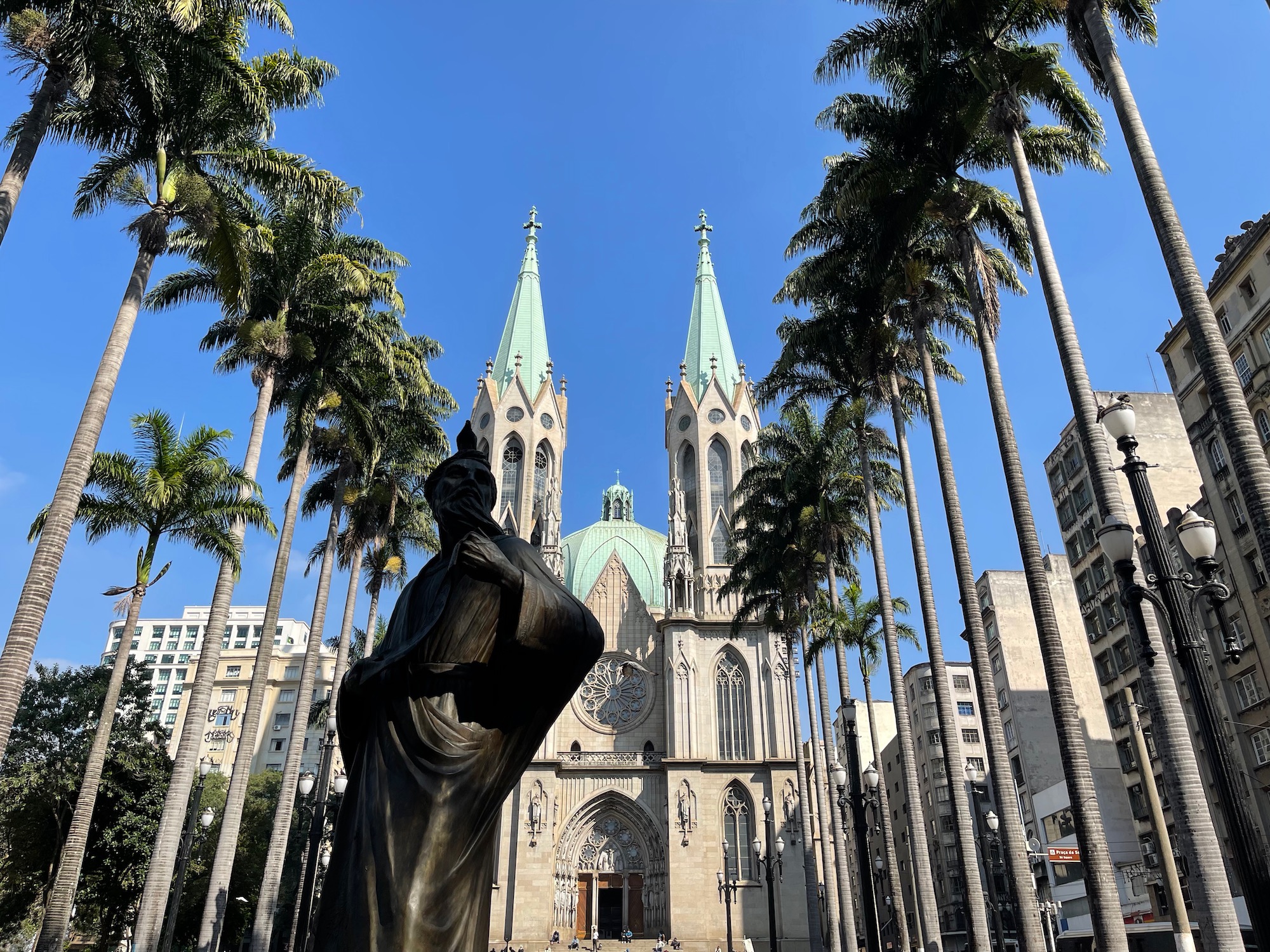 a statue in front of São Paulo Cathedral with palm trees