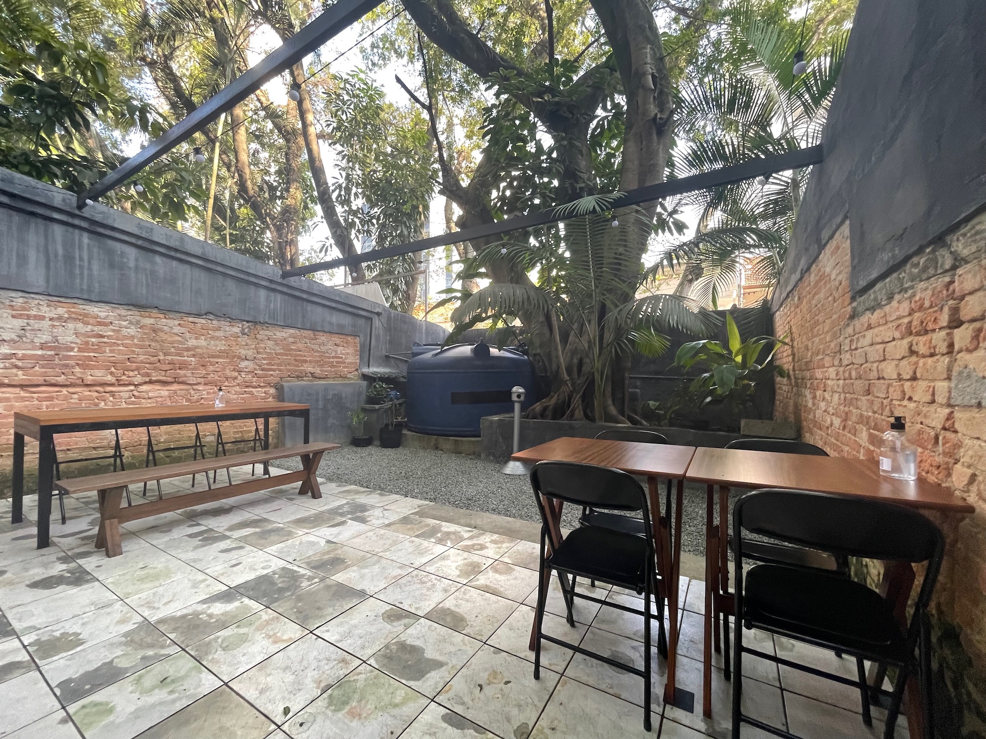 a table and chairs outside with trees and a brick wall