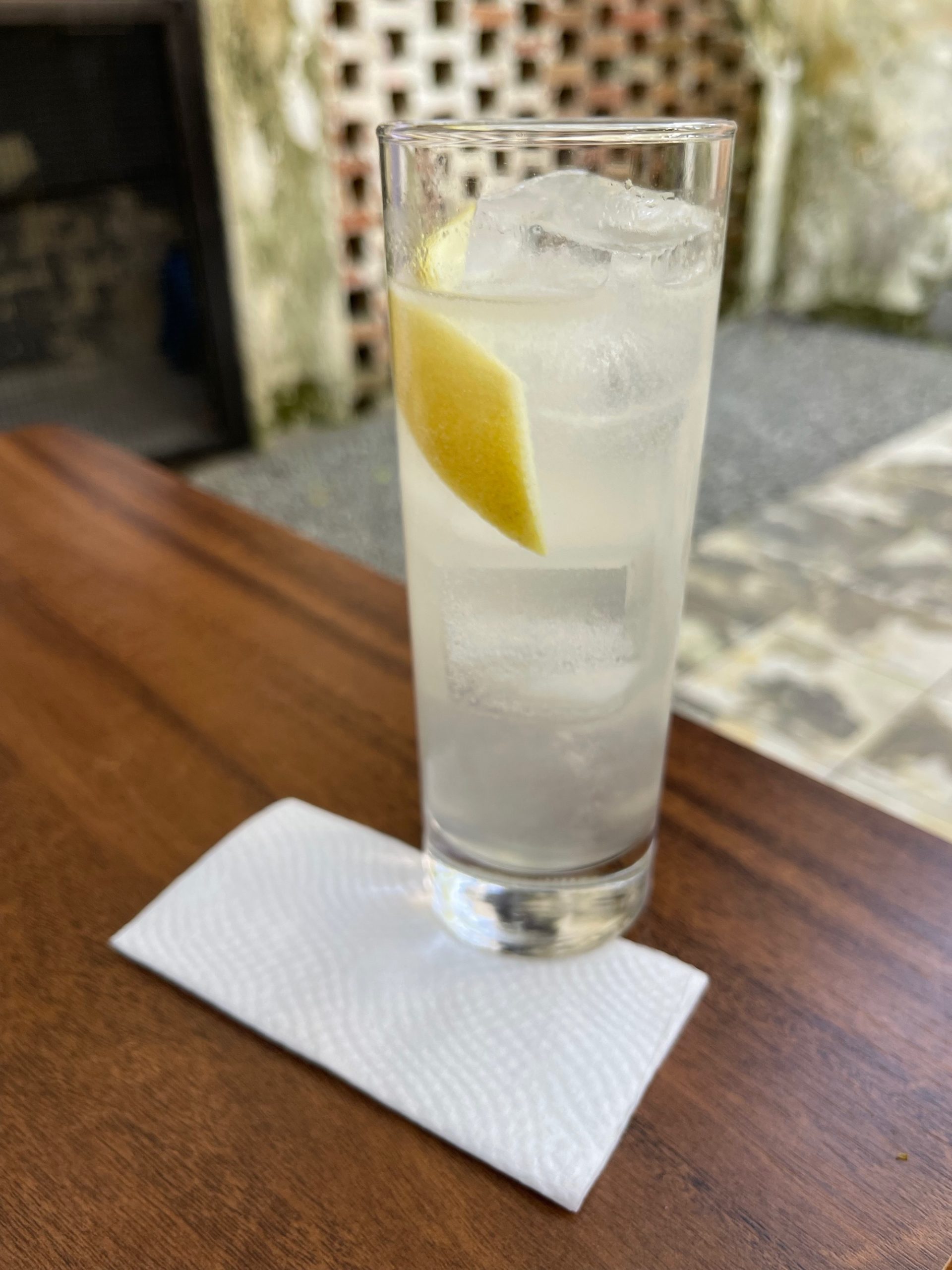 a glass of water with ice and a slice of lemon on a napkin
