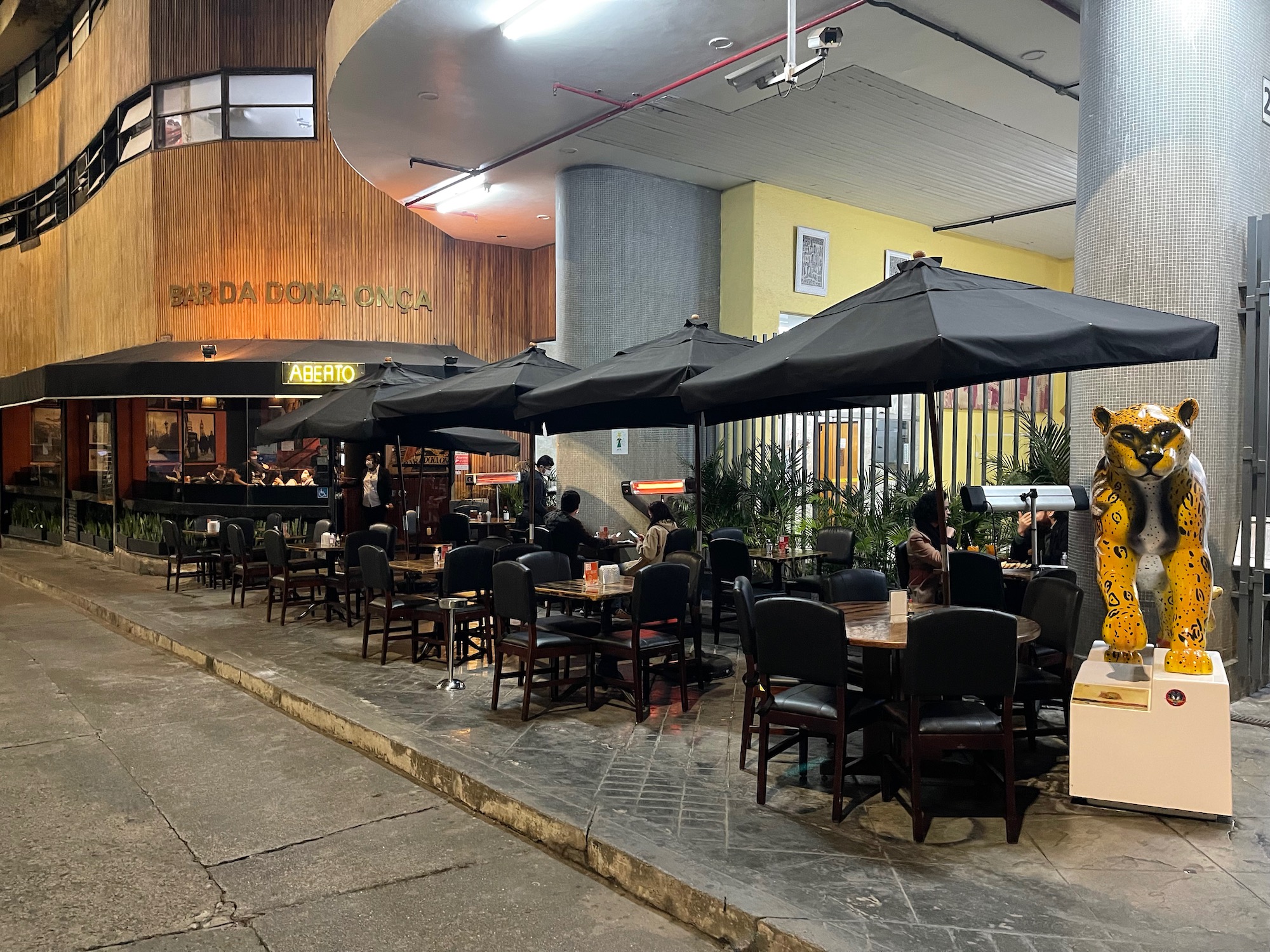 a group of people sitting at tables and umbrellas outside of a building