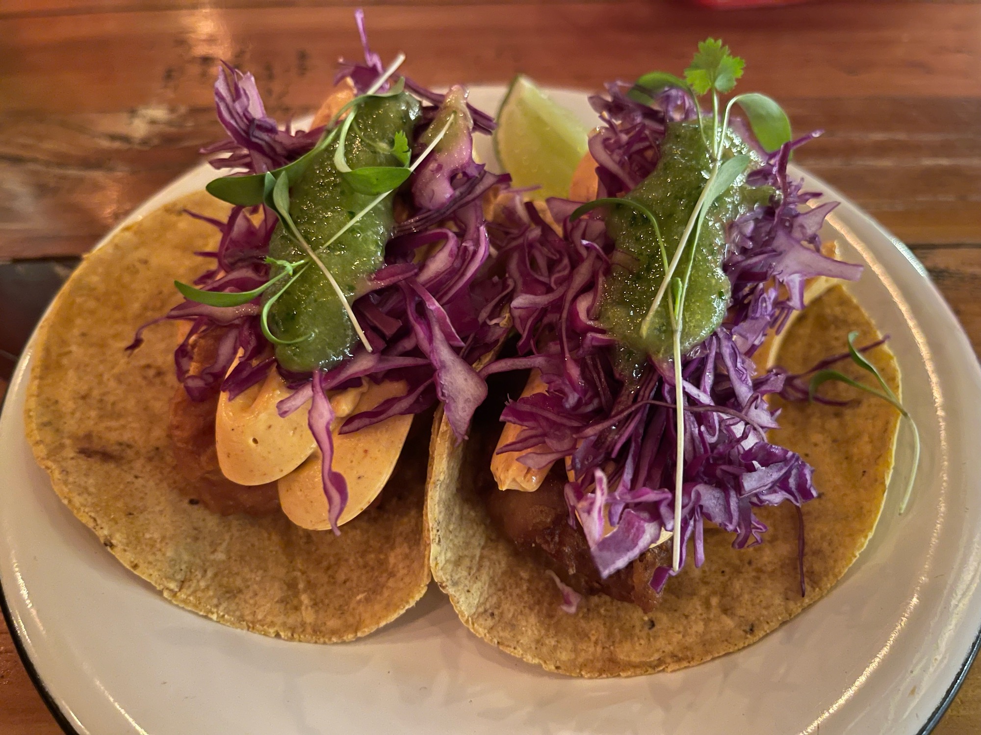 a plate of tacos with purple cabbage and lime