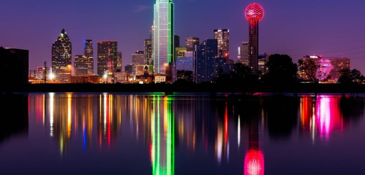 a city skyline with colorful lights reflecting on water