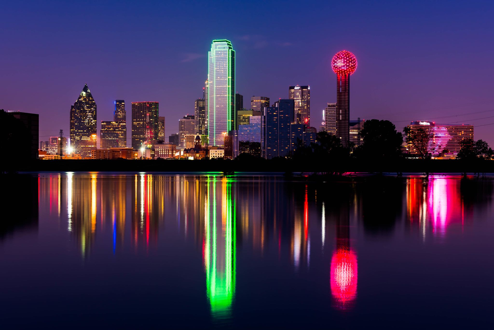 a city skyline with colorful lights reflecting on water