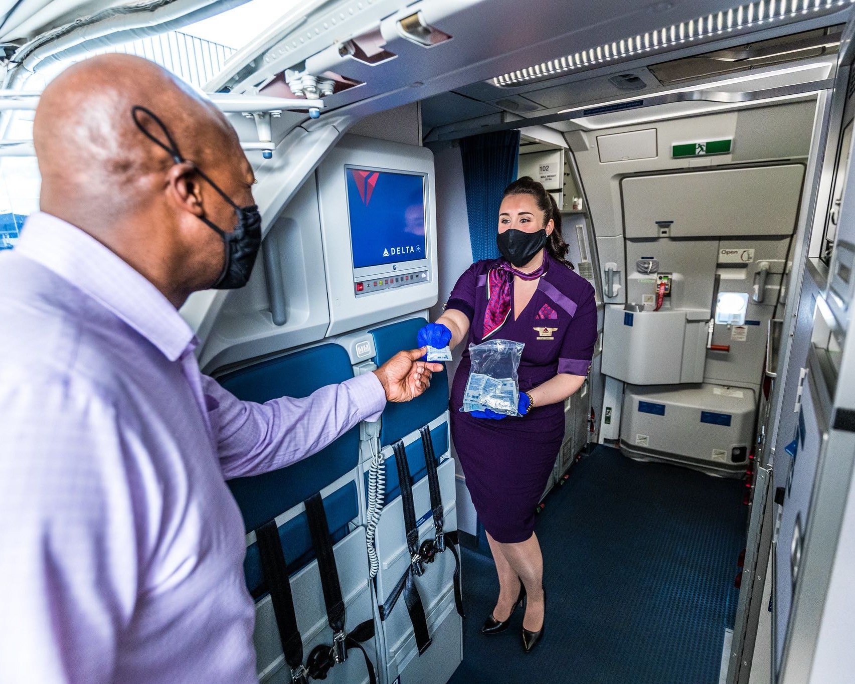 a woman wearing a face mask and holding a bag of food in a plane