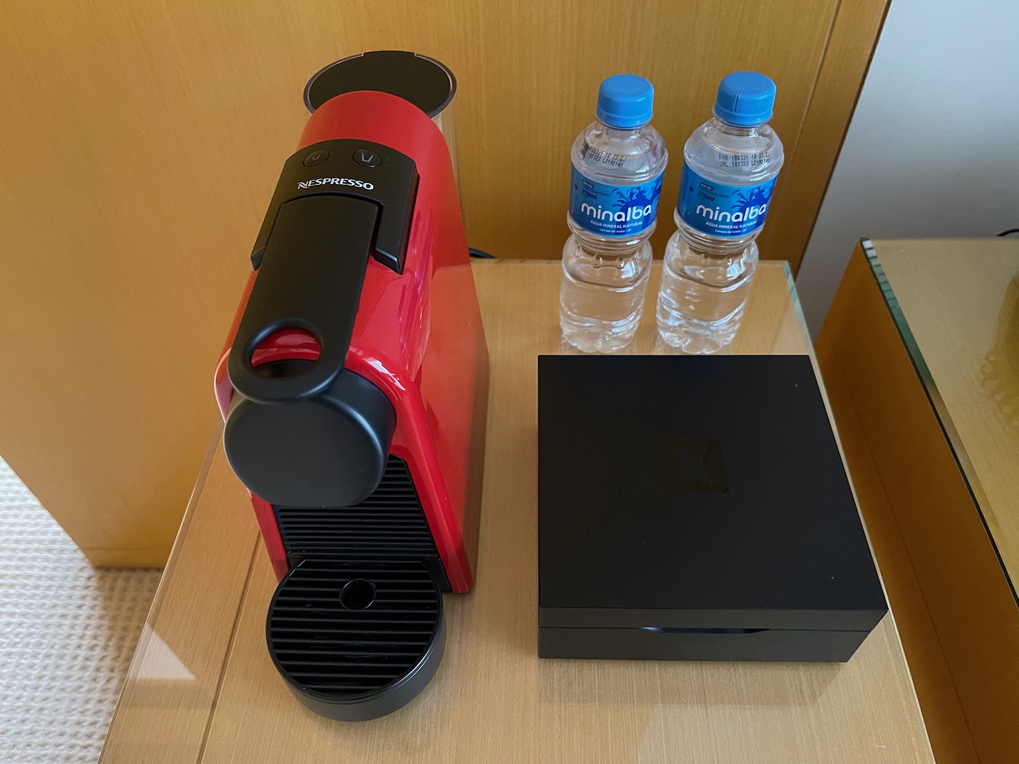 a red coffee machine and two water bottles on a table