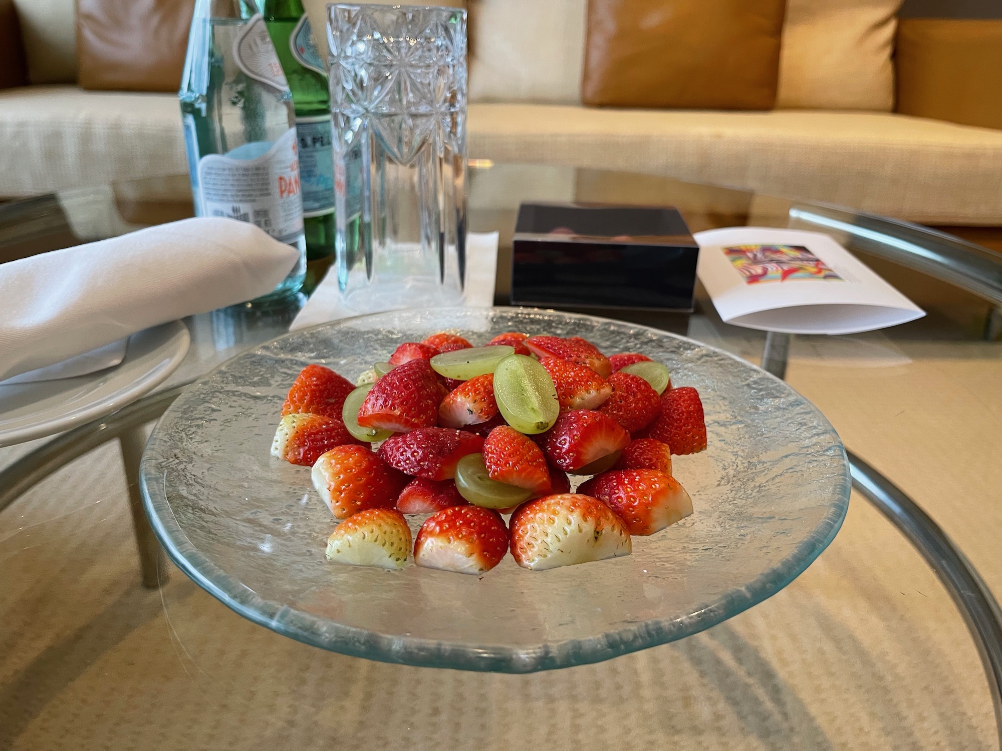 a plate of strawberries and grapes on a glass table