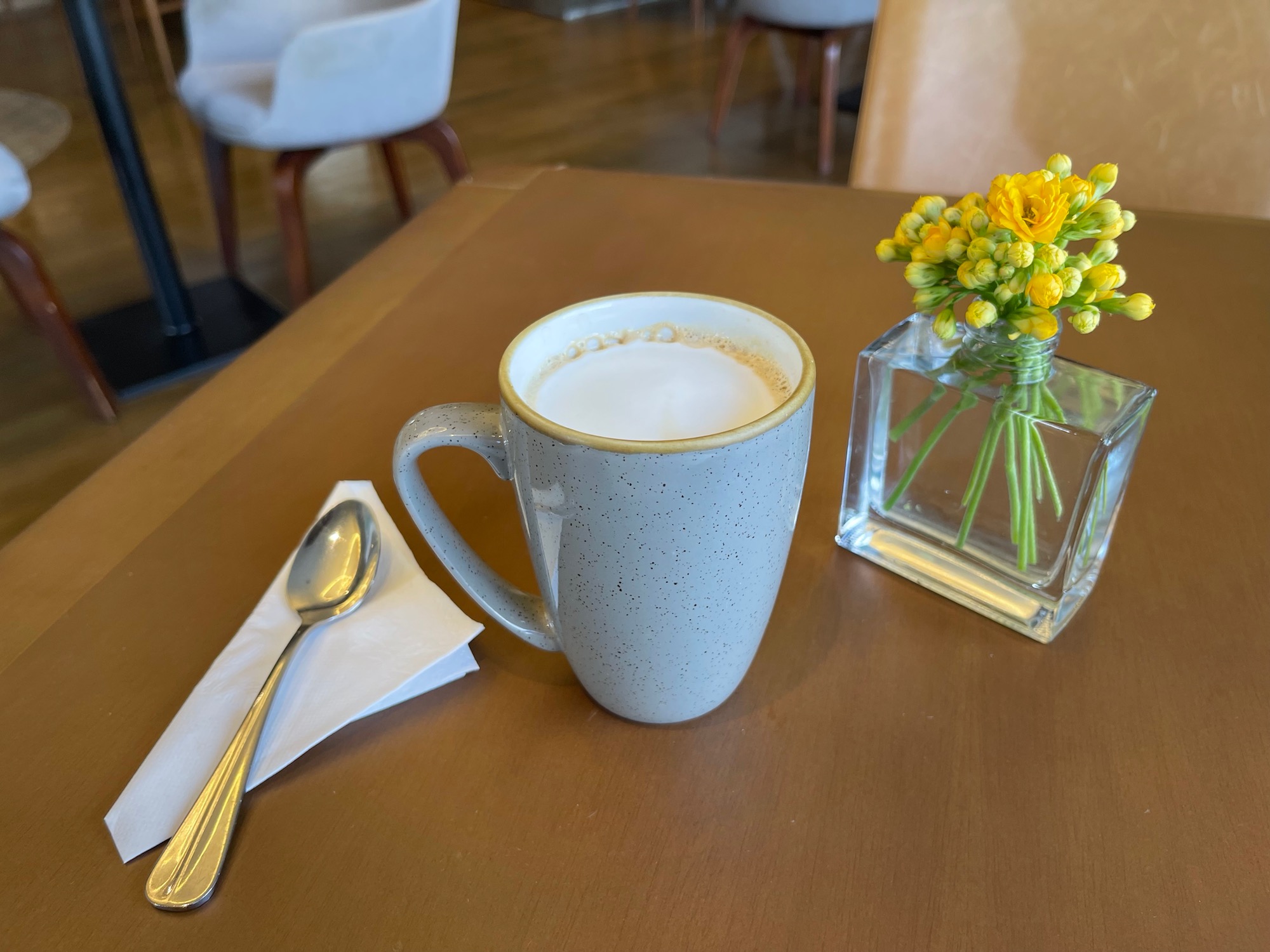 a cup of coffee and a vase of flowers on a table