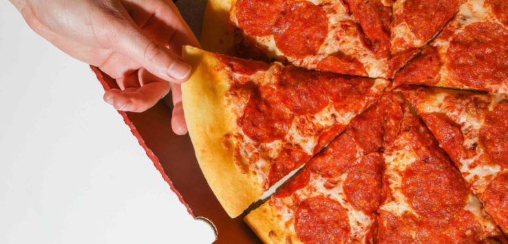 a hand taking a slice of pizza out of a box