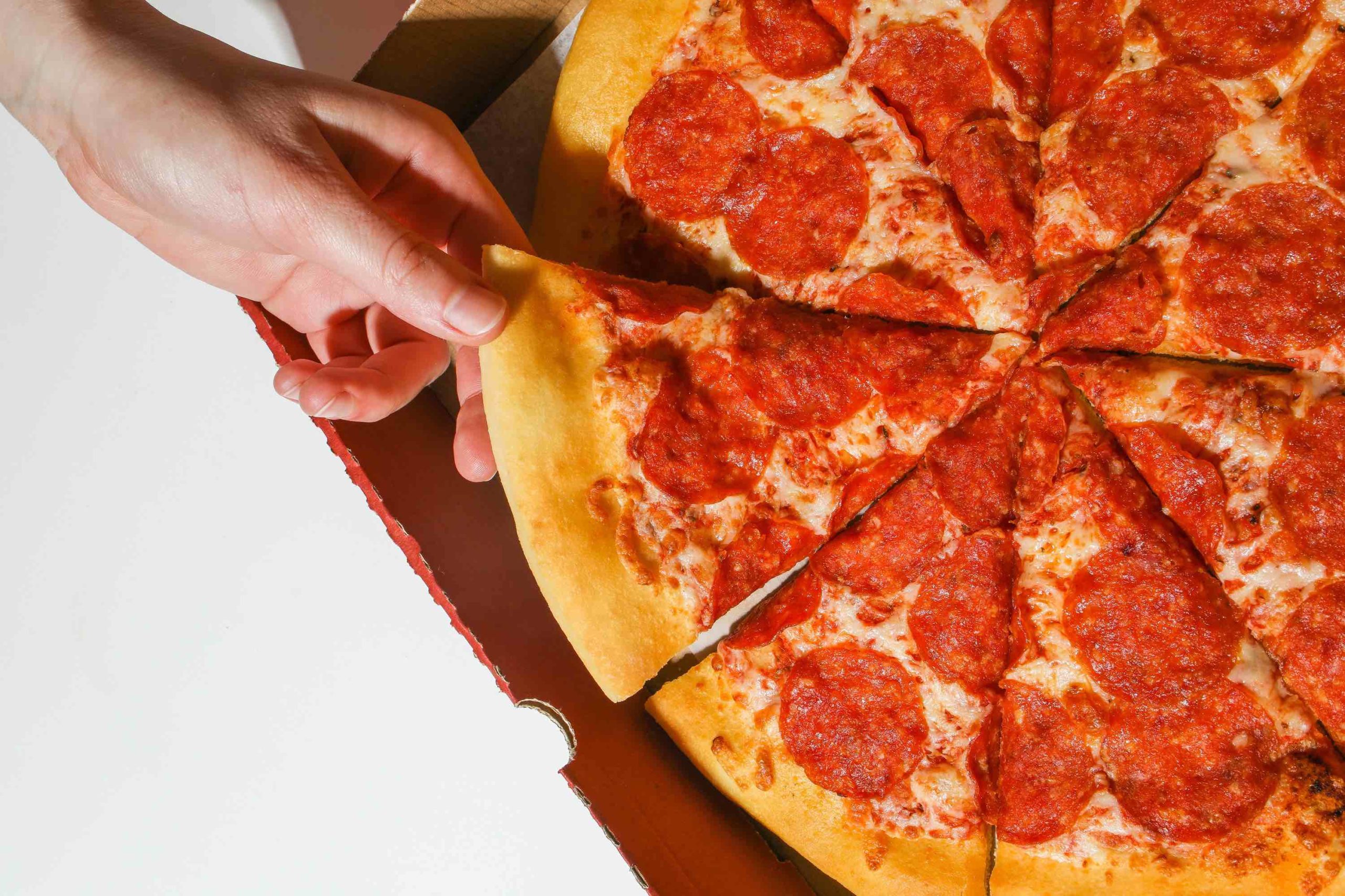 a hand taking a slice of pizza out of a box