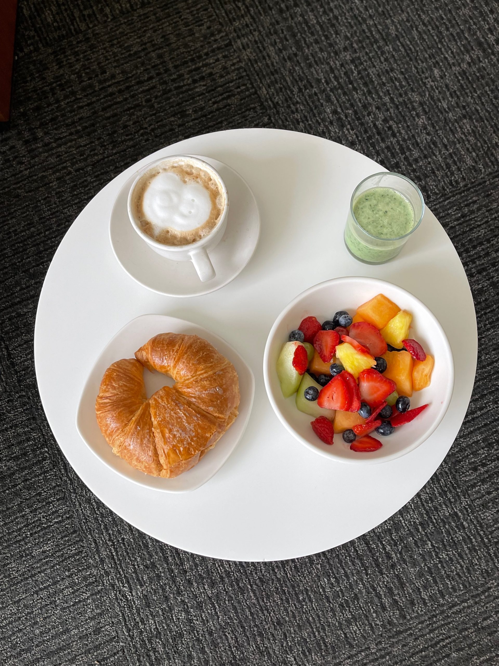a croissant and fruit on a white plate