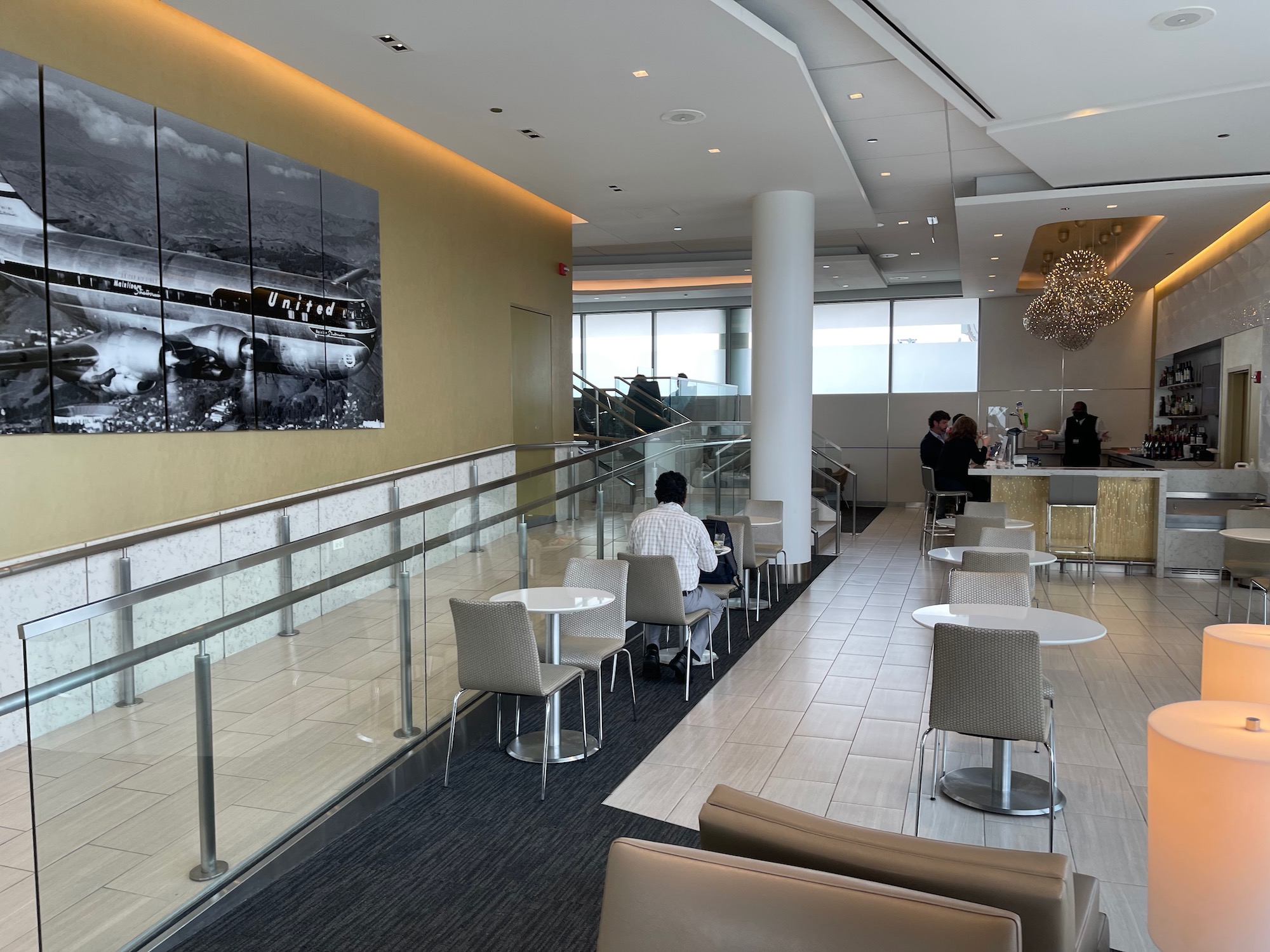 a room with a glass railing and tables and chairs