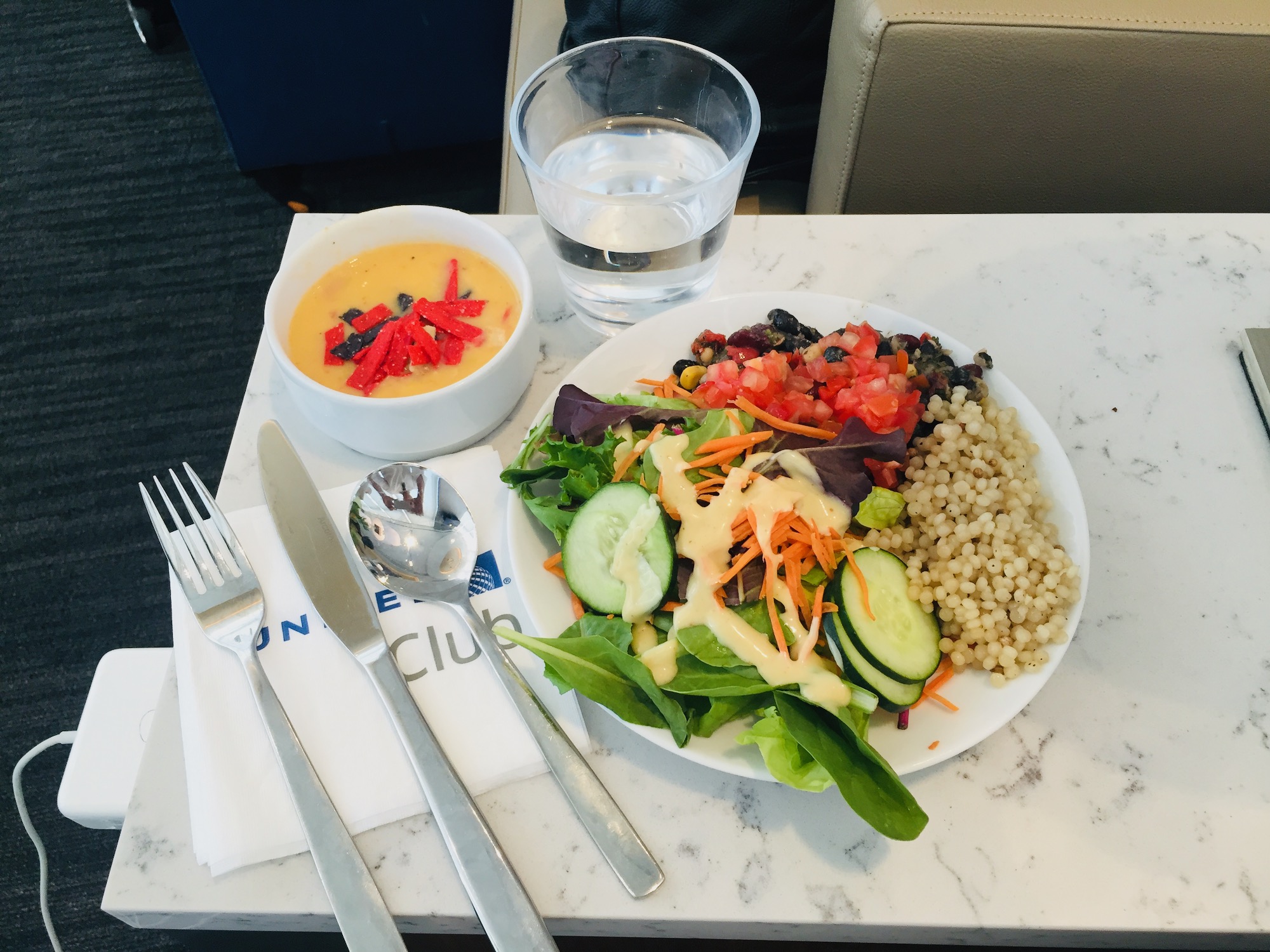 a plate of salad and a bowl of soup and a glass of water