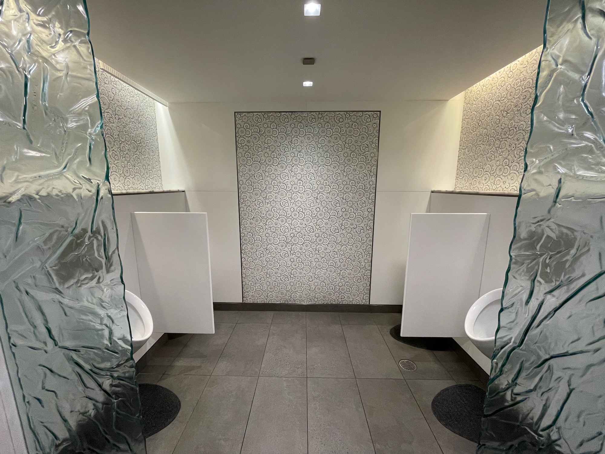 a bathroom with urinals and a glass wall