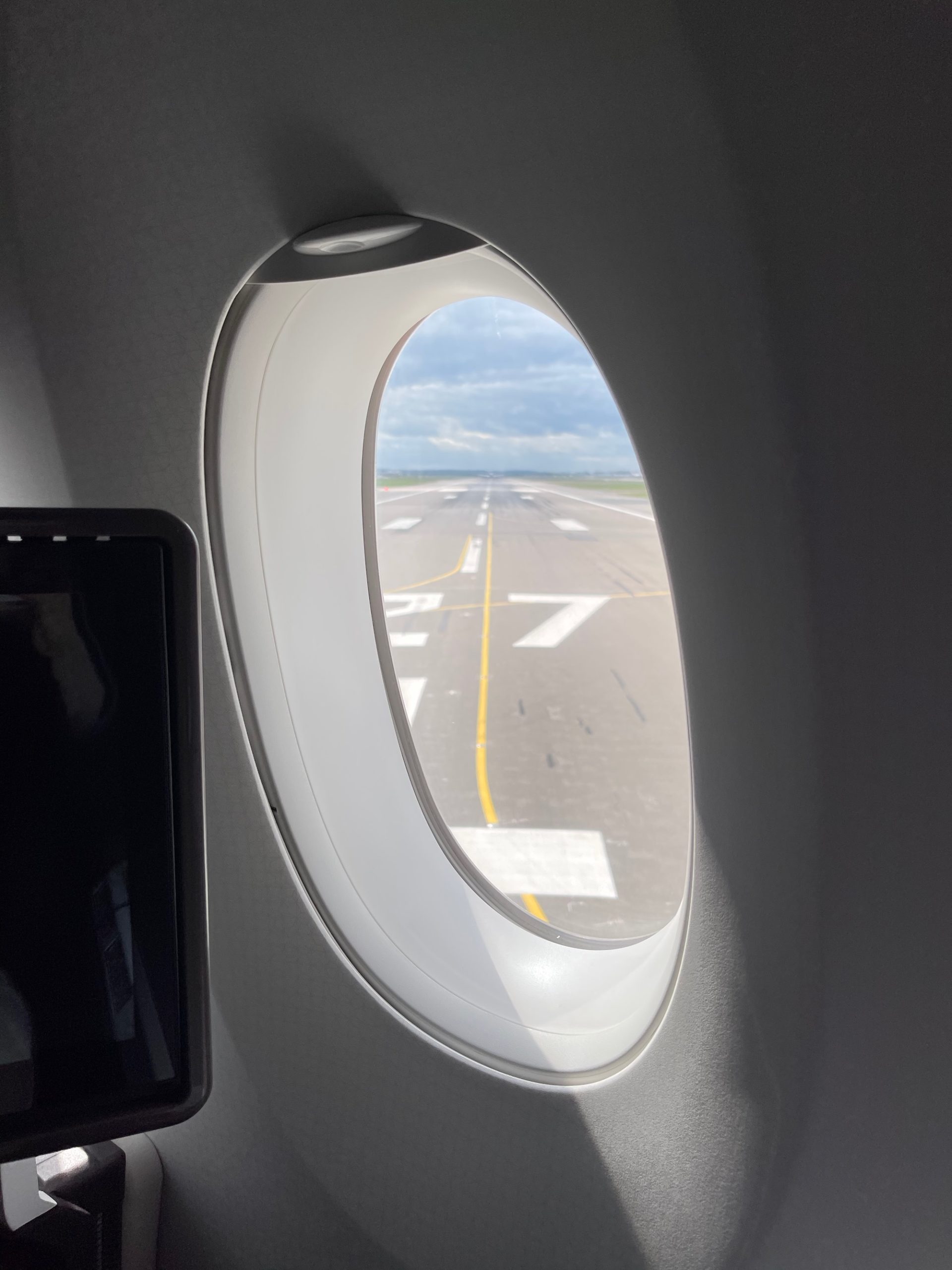 an airplane window with a runway and a screen