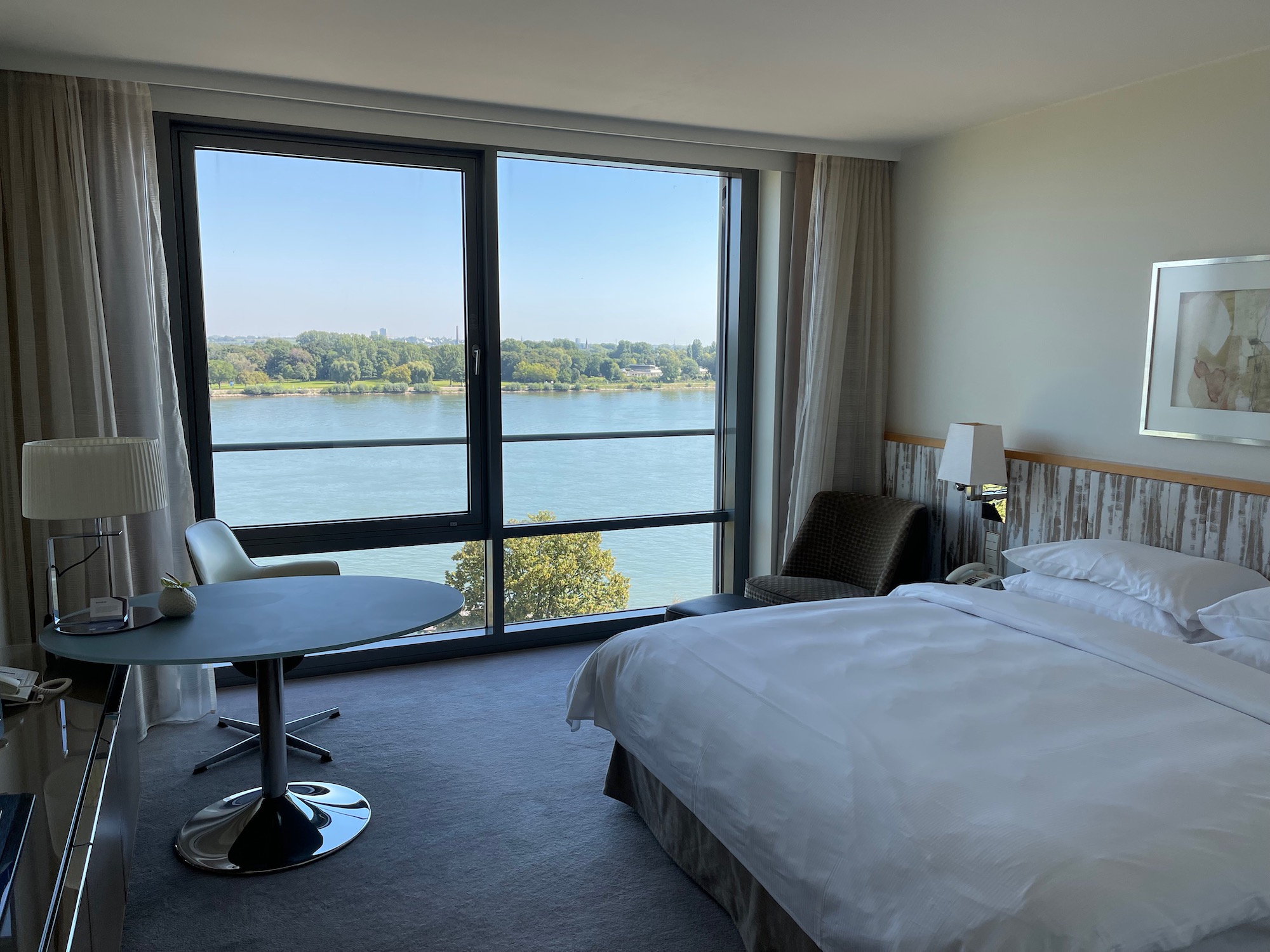 a room with a bed and a table and chairs by a large window