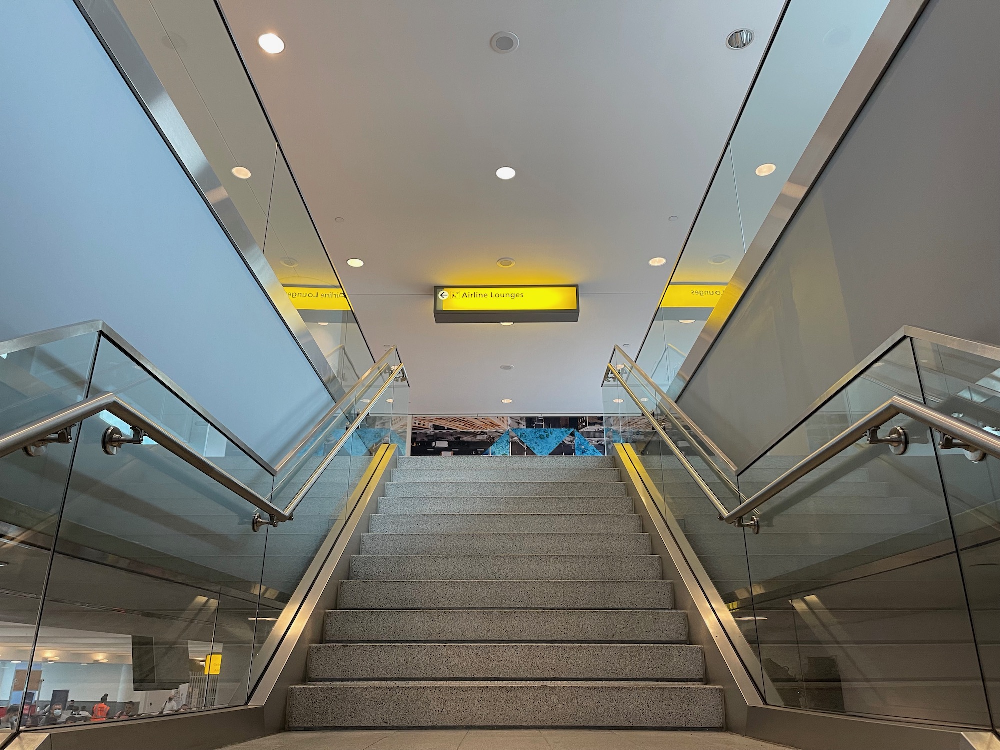 a staircase with glass railings and a yellow sign