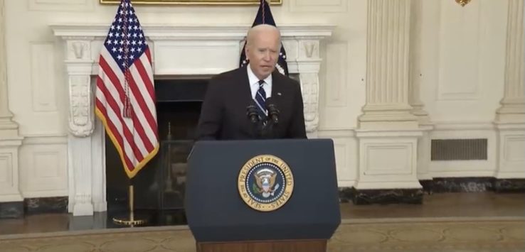 a man standing at a podium with microphones