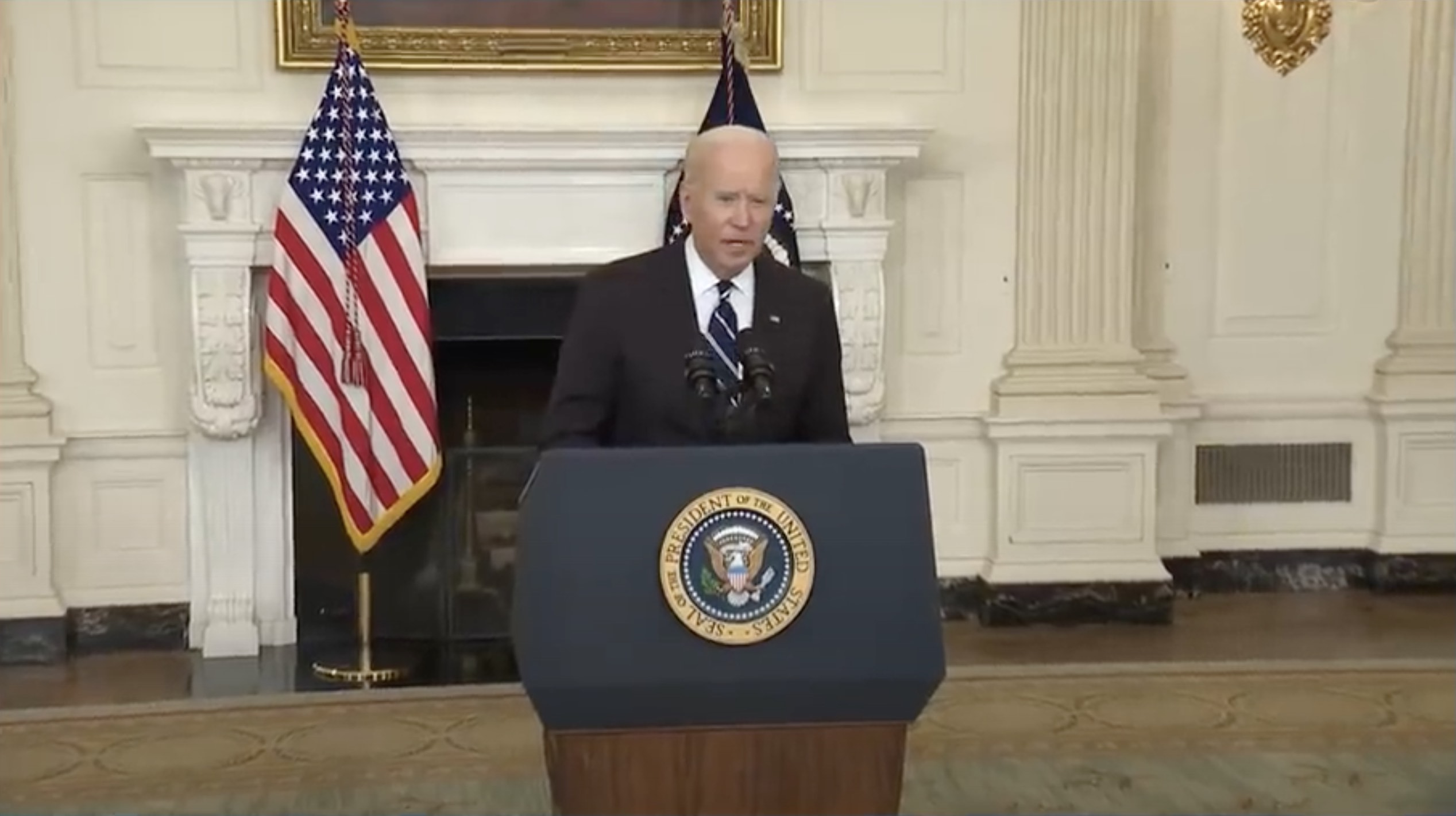 a man standing at a podium with microphones