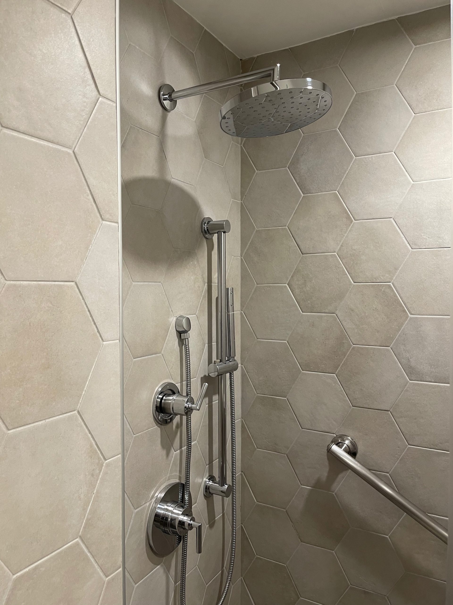 a shower with a shower head and handrails