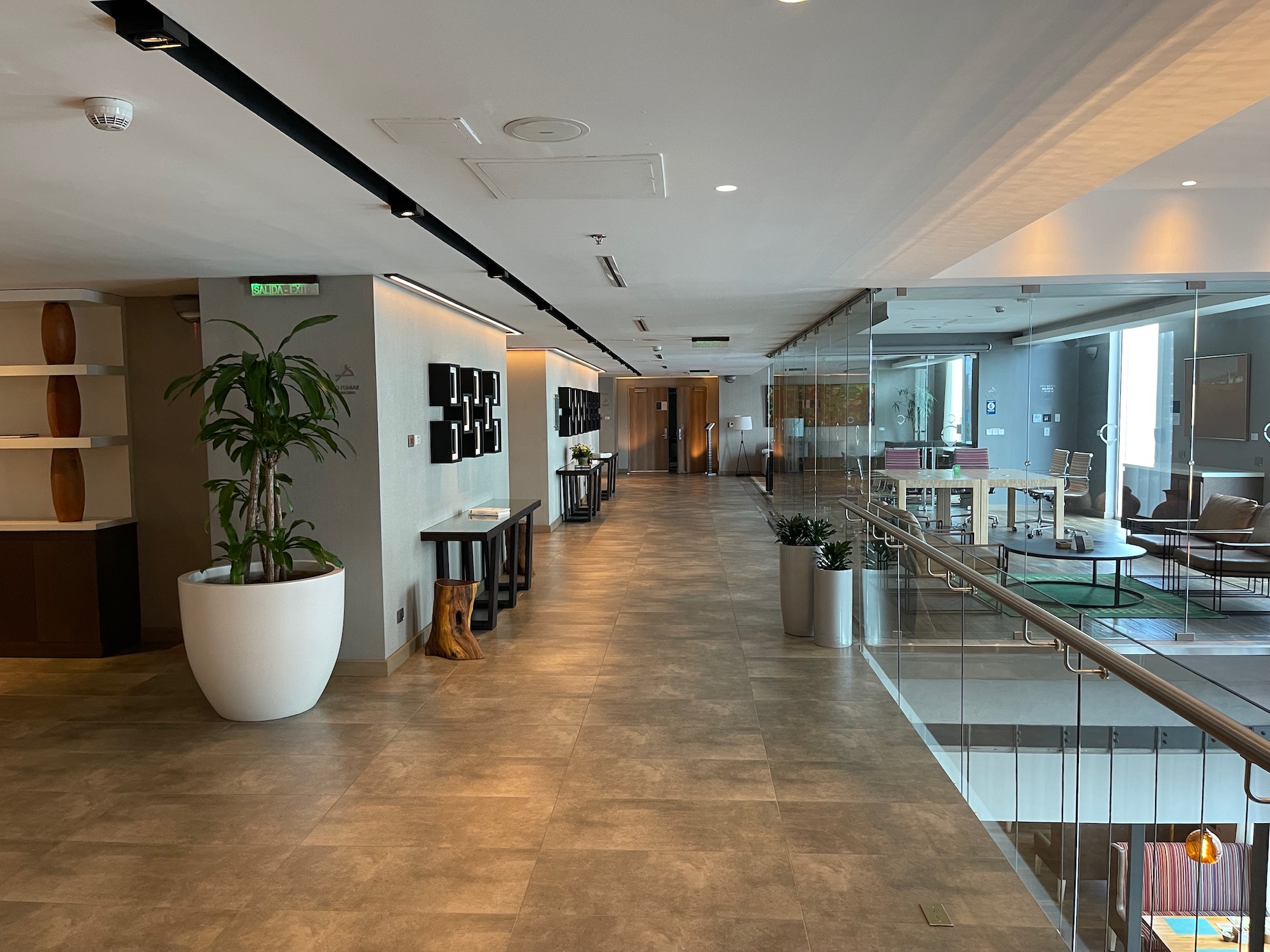 a hallway with a glass wall and a green table